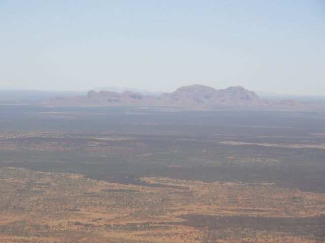 Am Horizont sieht man die Olgas, eine Felsformation 50 km von Ayers Rock entfernt.