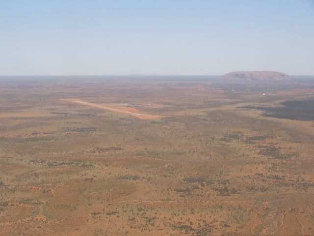Jetz sieht man ihn, den Ayers Rock. Modern erschlossen mit dazugehoeriger Landepiste.