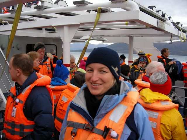 Sabine mit Schwimmweste inmitten illustrer Mitpassagiere.