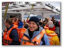 Sabine mit Schwimmweste inmitten illustrer Mitpassagiere.